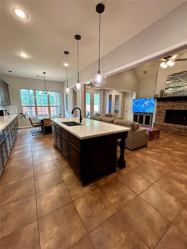 kitchen with sink, pendant lighting, vaulted ceiling, a kitchen island with sink, and a fireplace