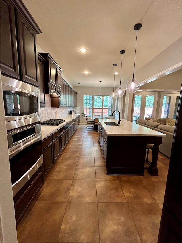 kitchen with dark brown cabinetry, a kitchen island with sink, sink, and stainless steel appliances