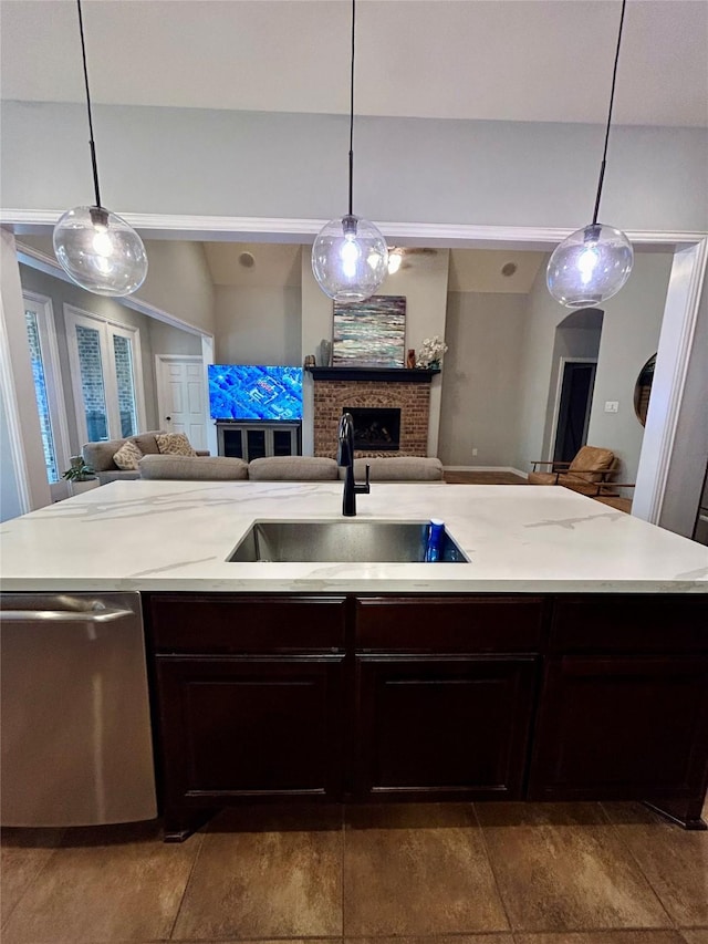 kitchen featuring a fireplace, dark brown cabinetry, sink, dishwasher, and hanging light fixtures