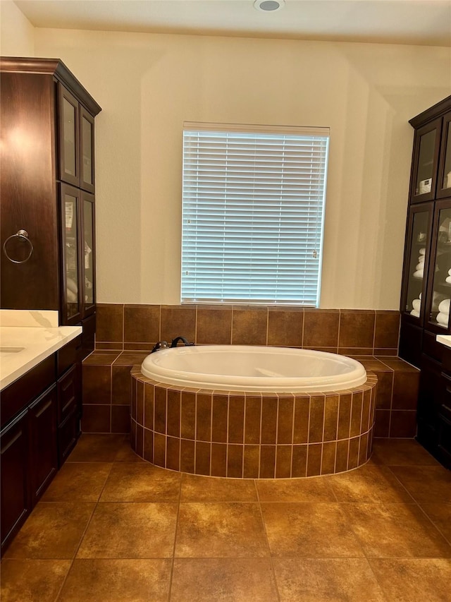 bathroom with tile patterned floors, tiled bath, and vanity