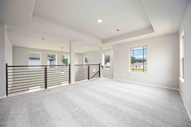 carpeted spare room featuring a tray ceiling