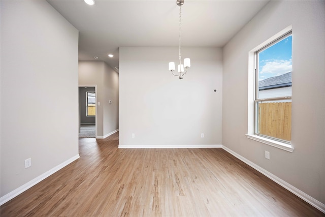 spare room featuring an inviting chandelier and light wood-type flooring