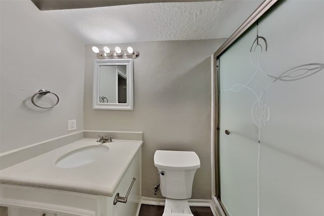 bathroom with toilet, vanity, a textured ceiling, and walk in shower