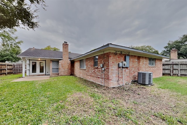 rear view of property featuring a yard, a patio, and central air condition unit