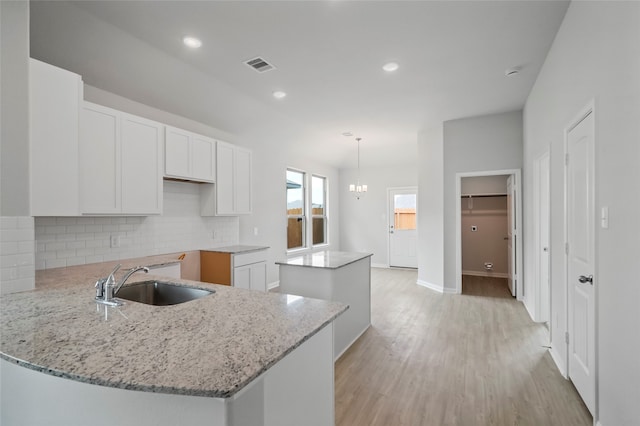 kitchen featuring kitchen peninsula, white cabinetry, a kitchen island, and sink