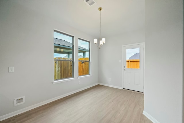 empty room featuring light wood-type flooring and a notable chandelier