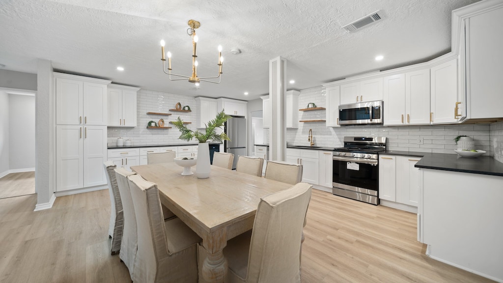 dining space featuring a textured ceiling, light hardwood / wood-style flooring, and sink