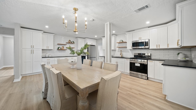 dining space featuring a textured ceiling, light hardwood / wood-style flooring, and sink