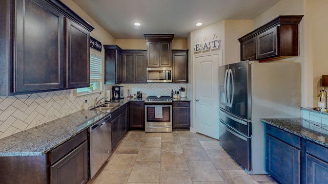 kitchen with sink, dark stone countertops, decorative backsplash, dark brown cabinets, and appliances with stainless steel finishes