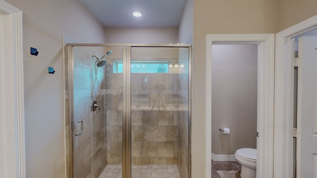 bathroom featuring a shower with shower door and toilet