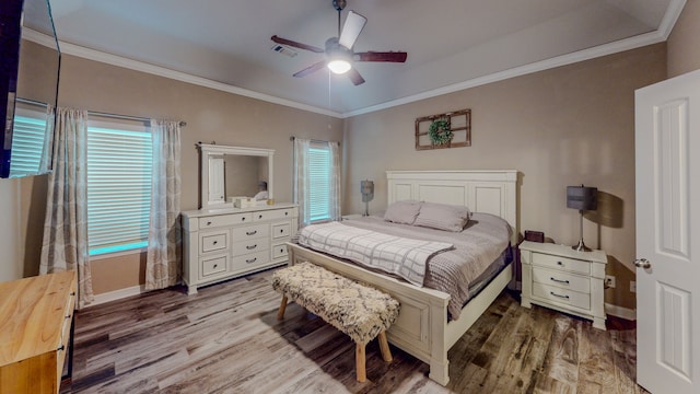 bedroom featuring multiple windows, ceiling fan, hardwood / wood-style floors, and ornamental molding