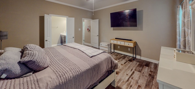 bedroom with hardwood / wood-style floors, ornamental molding, and connected bathroom