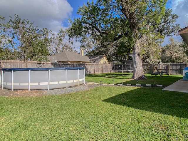 view of yard featuring a fenced in pool and a trampoline