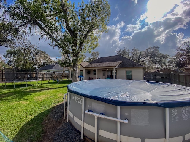 view of pool with a trampoline and a yard