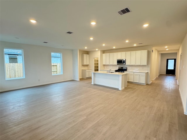 kitchen with sink, a center island with sink, appliances with stainless steel finishes, light hardwood / wood-style floors, and white cabinets