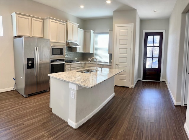 kitchen featuring sink, stainless steel appliances, light stone counters, dark hardwood / wood-style floors, and a kitchen island with sink