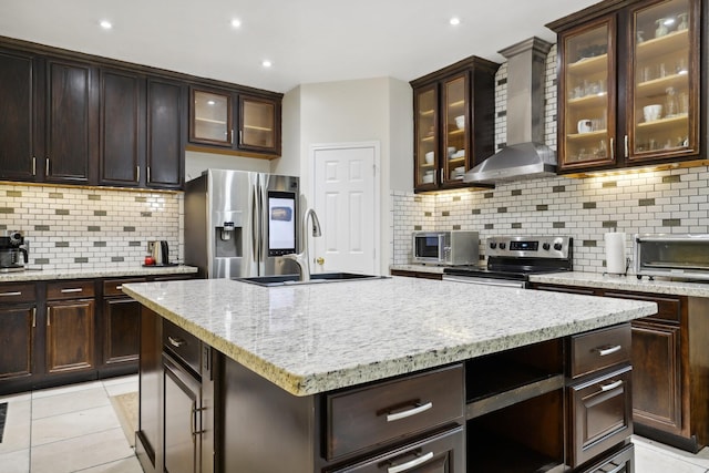 kitchen featuring glass insert cabinets, wall chimney exhaust hood, and appliances with stainless steel finishes