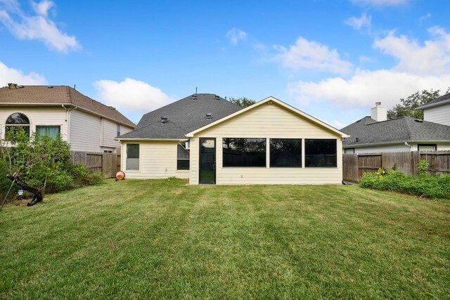 rear view of property featuring a lawn and a sunroom