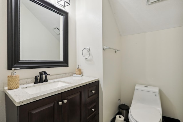 bathroom featuring vanity, toilet, and lofted ceiling