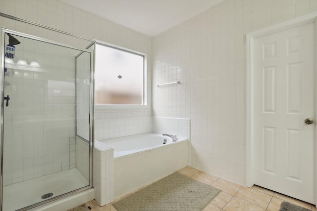 bathroom with tile patterned flooring, a garden tub, tile walls, and a shower stall