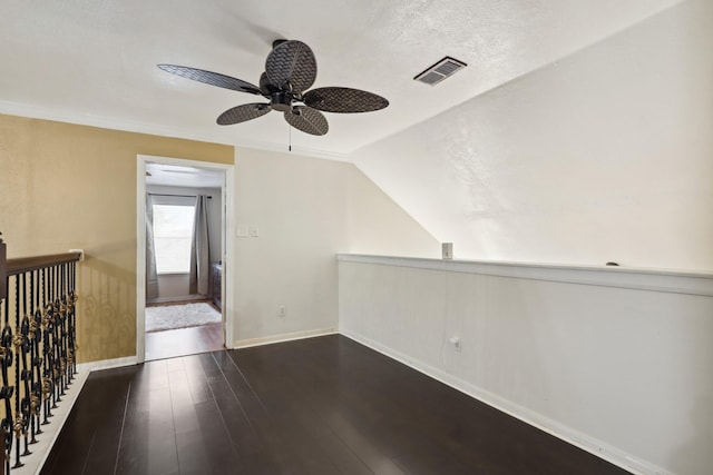 empty room with ceiling fan, dark hardwood / wood-style flooring, lofted ceiling, and a textured ceiling