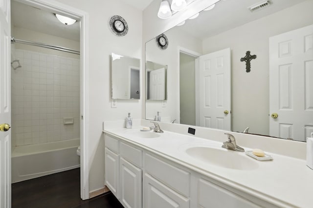 full bathroom featuring vanity, toilet, wood-type flooring, and tiled shower / bath combo