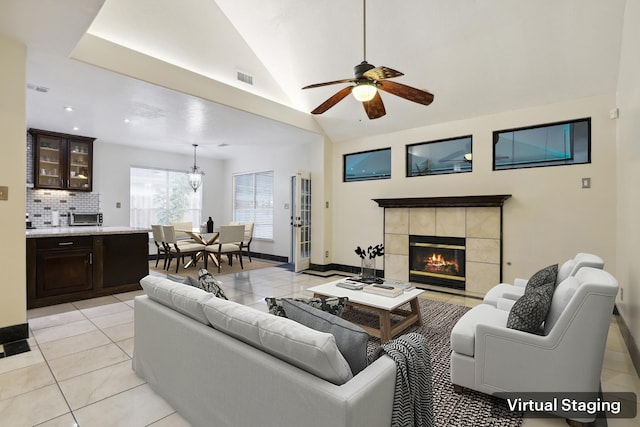 living area featuring lofted ceiling, light tile patterned flooring, a fireplace, visible vents, and baseboards