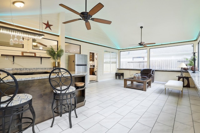 interior space with ceiling fan, high vaulted ceiling, and light tile patterned flooring