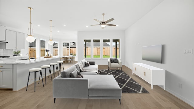 living room with ceiling fan, light hardwood / wood-style flooring, and sink