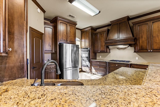 kitchen with sink, double oven, stainless steel fridge, custom range hood, and ornamental molding