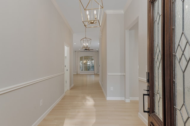 corridor with a notable chandelier, crown molding, and light hardwood / wood-style flooring