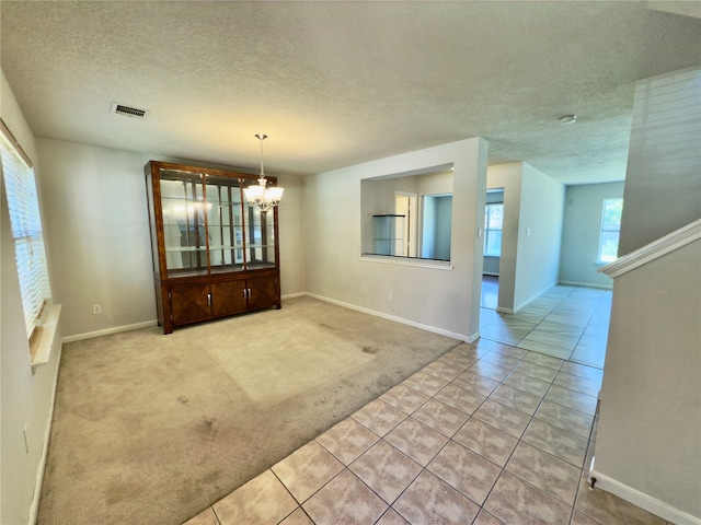 unfurnished dining area featuring a textured ceiling, light carpet, and a chandelier