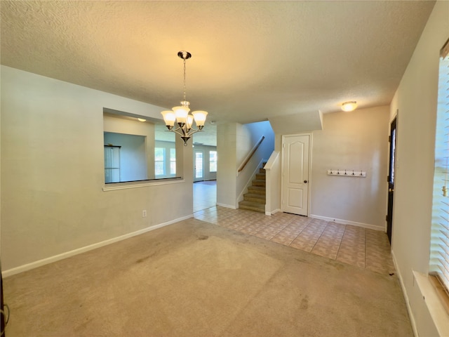 spare room with tile patterned floors, a notable chandelier, and a textured ceiling