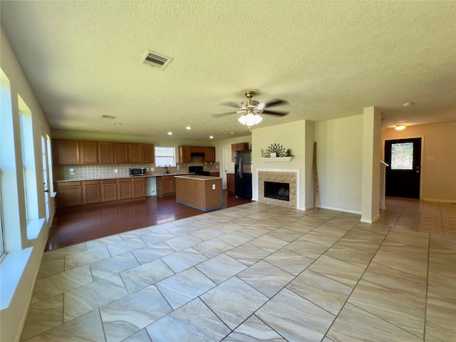 kitchen with plenty of natural light, ceiling fan, black fridge with ice dispenser, and backsplash