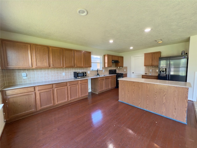 kitchen featuring gas stove, fridge with ice dispenser, sink, and a kitchen island