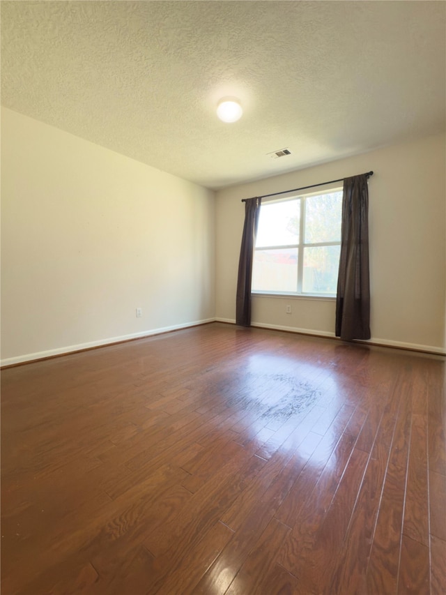 unfurnished room with a textured ceiling and dark hardwood / wood-style floors