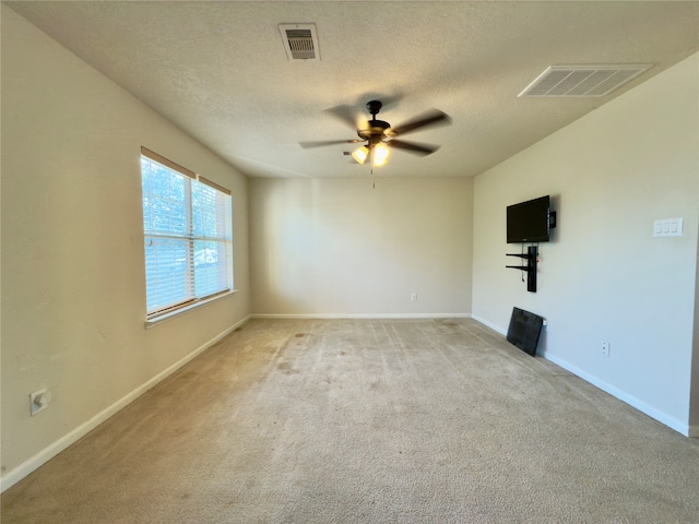 unfurnished room featuring ceiling fan, light colored carpet, and a textured ceiling