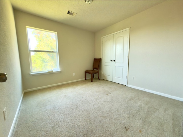 unfurnished bedroom with light carpet and a closet