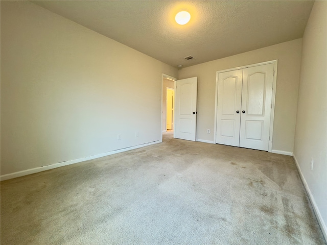 unfurnished bedroom with light carpet, a closet, and a textured ceiling