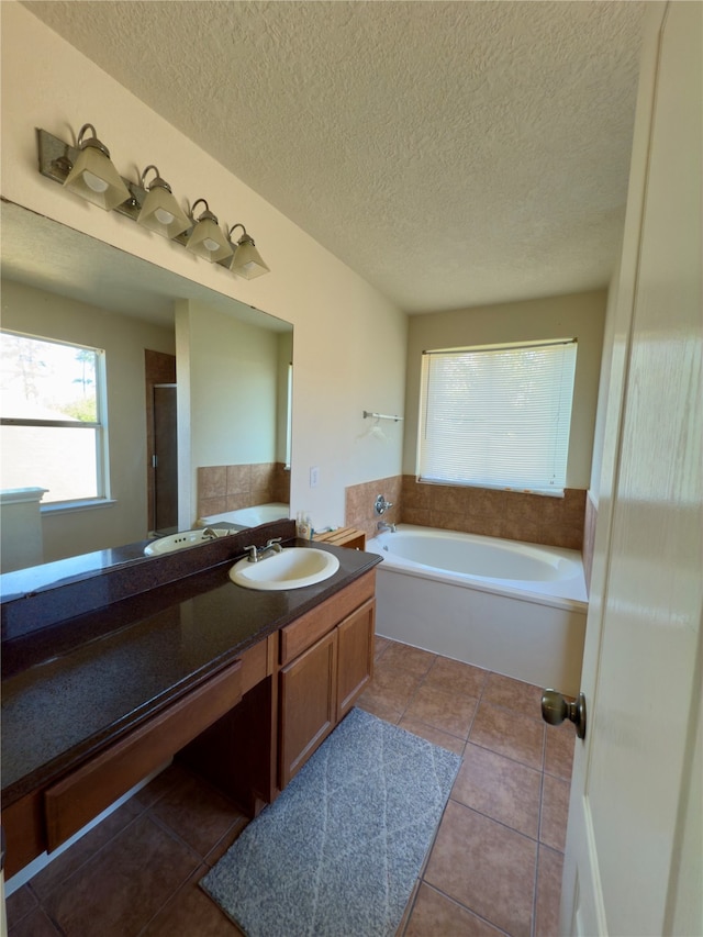 bathroom featuring tile patterned flooring, vanity, a bath, and a textured ceiling