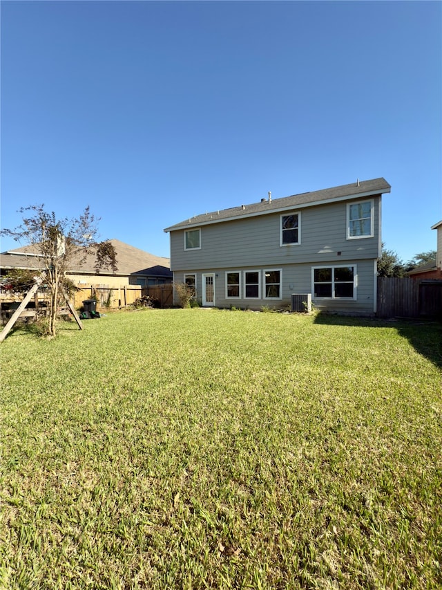 rear view of house with a lawn and central AC