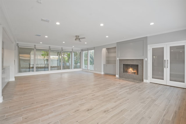 unfurnished living room with built in shelves, ceiling fan, light hardwood / wood-style floors, and ornamental molding