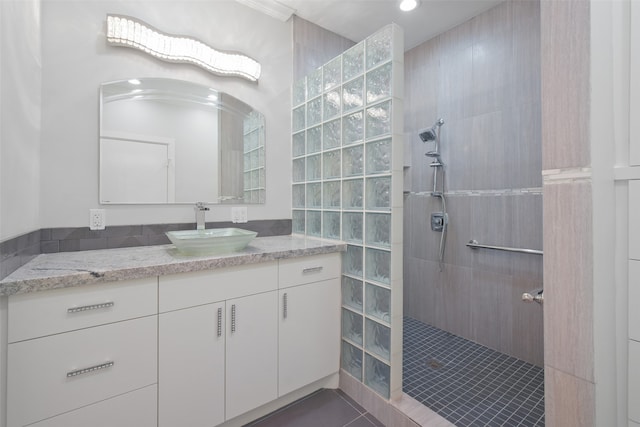 bathroom with tile patterned flooring, vanity, and a tile shower