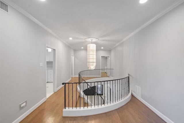 hall featuring hardwood / wood-style flooring, ornamental molding, and a chandelier