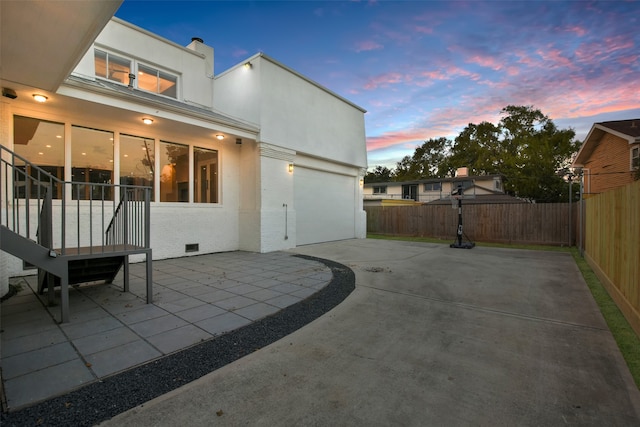 back house at dusk featuring a patio area