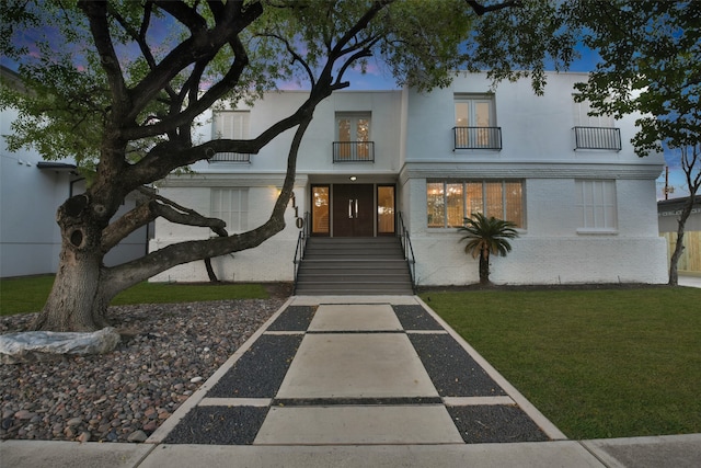 view of front of home with a lawn and a balcony