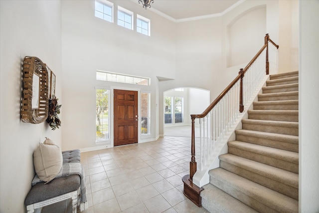 foyer featuring light tile patterned flooring, a high ceiling, and ornamental molding