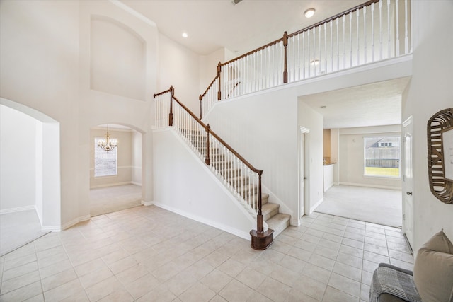 foyer with a notable chandelier, light carpet, and a high ceiling