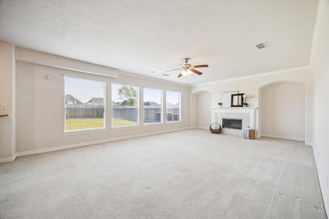 unfurnished living room featuring ceiling fan, ornamental molding, light carpet, and a tile fireplace