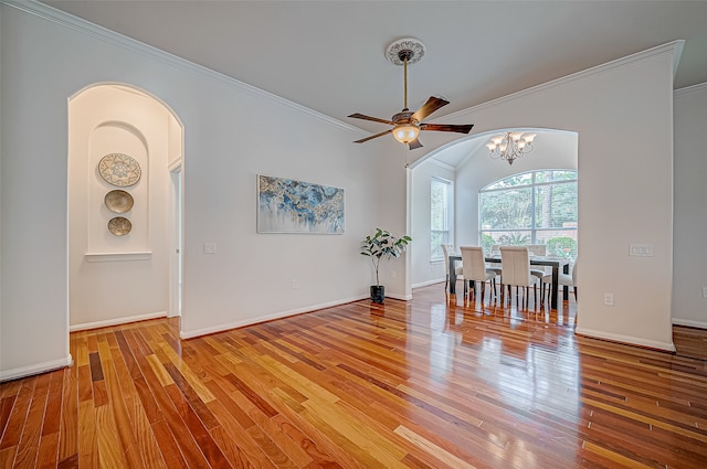 unfurnished dining area featuring ceiling fan with notable chandelier, light hardwood / wood-style floors, and crown molding